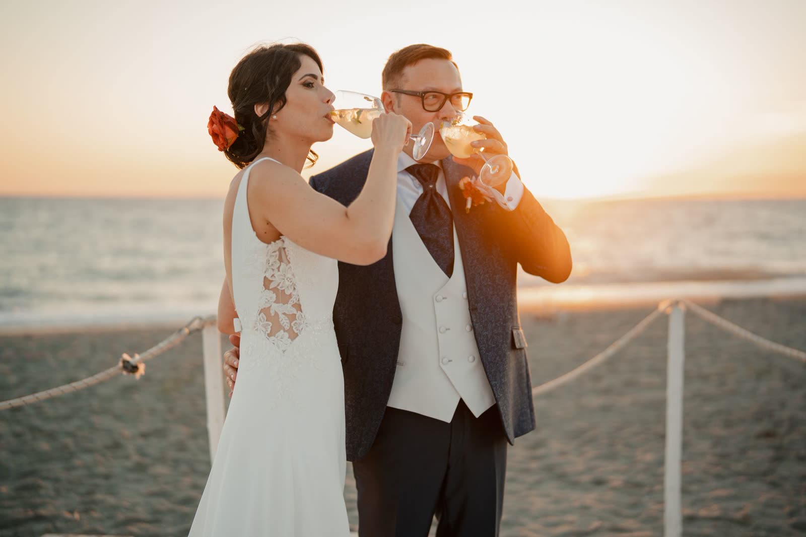 Brindis con copas de champán frente al mar al atardecer